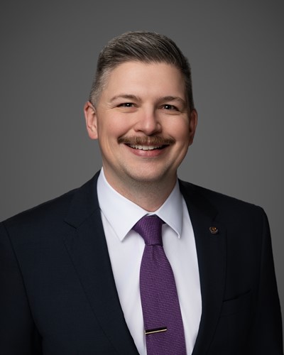 A picture of a man in a suit and tie smiling at the camera.