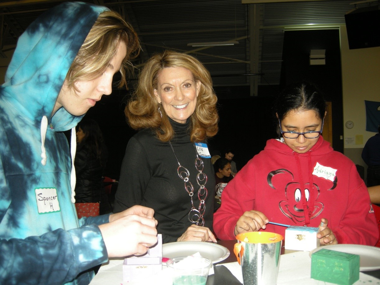 Lin Garretson stands next to two youths making art.