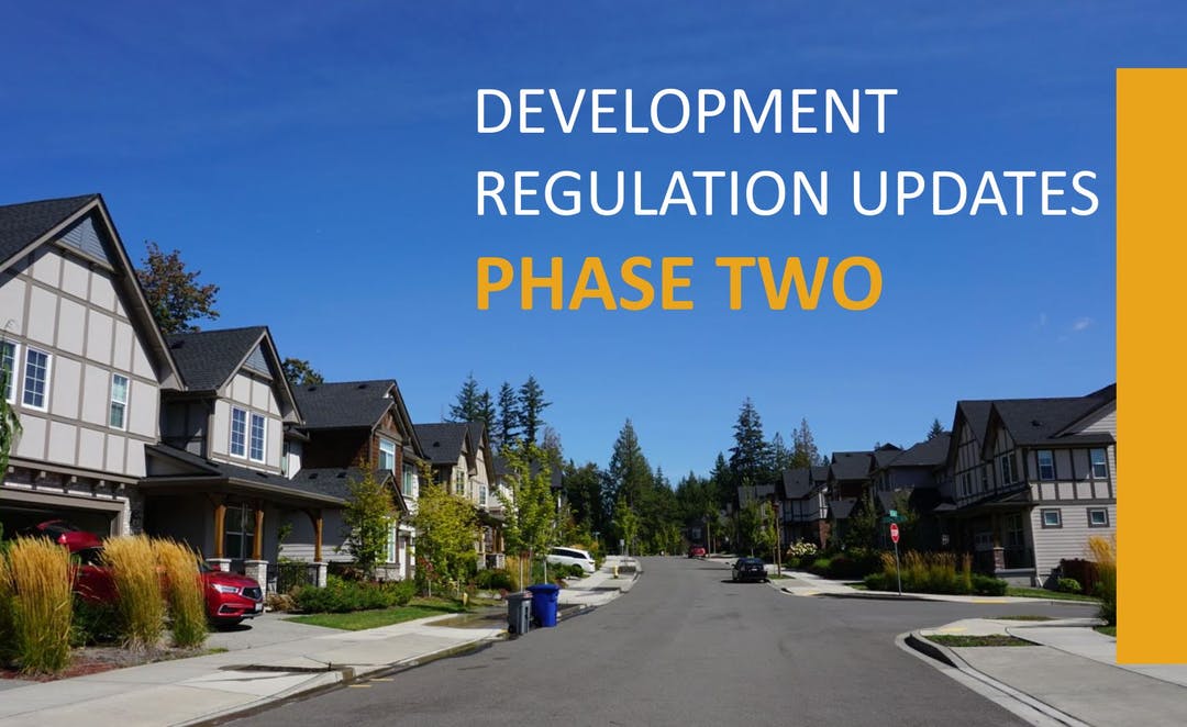 Photo of neighborhood street with two-story homes, sidewalks, and trees in the background. Words say: Development Regulation Updates Phase Two.